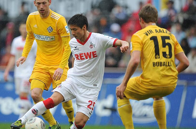 Kölns Kazuki Nagasawa (M) und Aalens Daniel Buballa (r) kämpfen um den Ball.