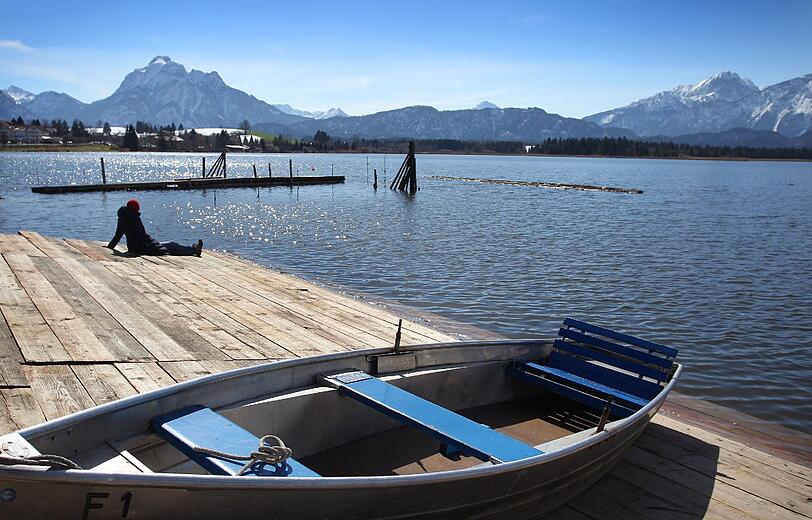 Im Sonnenlicht glitzert vor schneebedeckten Bergen der Hopfensee bei Hopferau (Bayern).