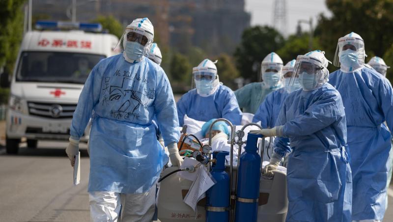 Medizinisches Personal in Schutzanzügen schiebt in Wuhan einen Covid-19-Patienten über eine Straße, um ihn in die Intensivstation zu verlegen. Medizinisches Personal in Schutzanzügen schiebt in Wuhan einen Covid-19-Patienten über eine Straße, um ihn in die Intensivstation zu verlegen.