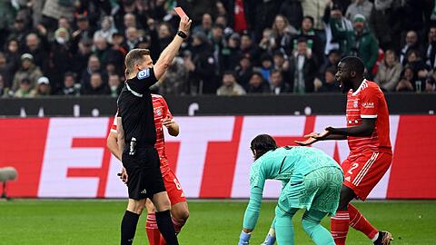 Schiedsrichter Tobias Welz zeigt Bayerns Dayot Upamecano (r) die rote Karte.