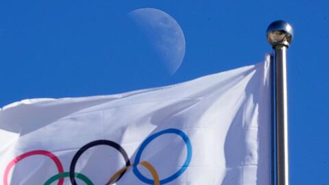 Eine olympischen Flagge weht vor blauem Himmel im Wind.