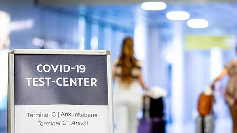 Ein Schild weist Reisende in einem Flughafen auf das Corona-Testzentrum hin.