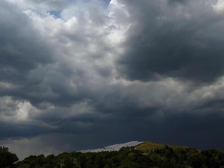 Wolken ziehen über ein Feld. Foto: picture alliance / dpa/Archivbild