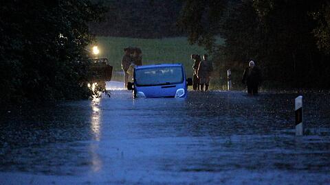 Ein Fahrzeug steht von Wasser umgeben auf einer überfluteten Straße am Bodensee.