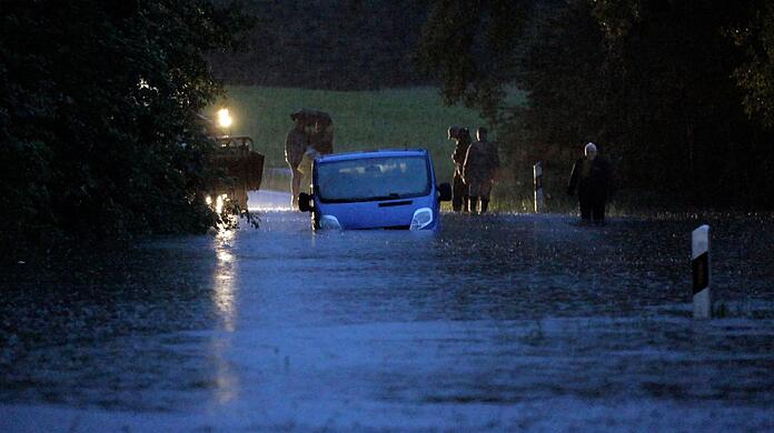 Ein Fahrzeug steht von Wasser umgeben auf einer überfluteten Straße am Bodensee.