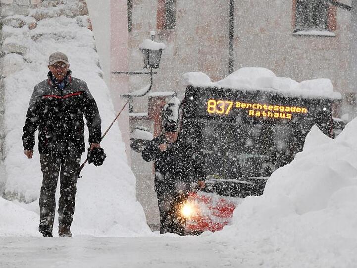 Ein Mann geht auf einer schneebedeckten Straße in Berchtesgaden (Bayern) entlang. Foto: Tobias Hase