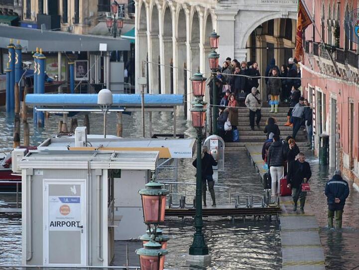 Sightseeing auf Stegen: Touristen in der überfluteten Altstadt von Venedig.