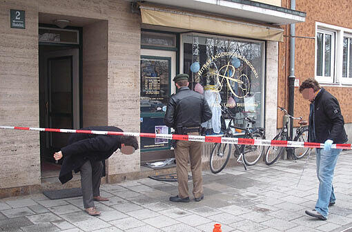 Blut klebt auf dem Pflaster. Ein Polizist sichert die Spuren.