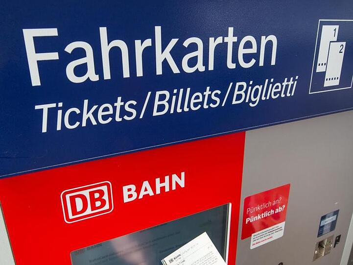 Eine Person hält ein Ticket vor einem Fahrkartenautomaten der Deutschen Bahn. Foto: Armin Weigel/dpa