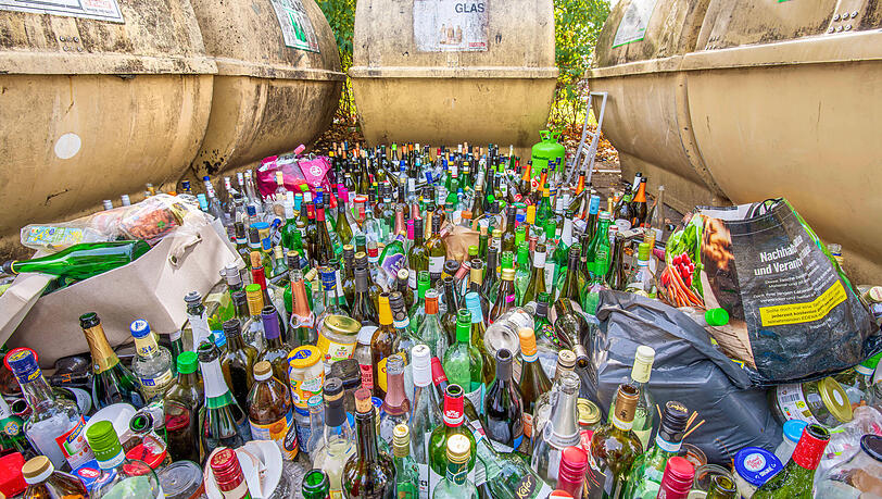 Unzählige leere Glasflaschen stehen vor vollen Altglas-Containern in Waldperlach. (Archivbild)