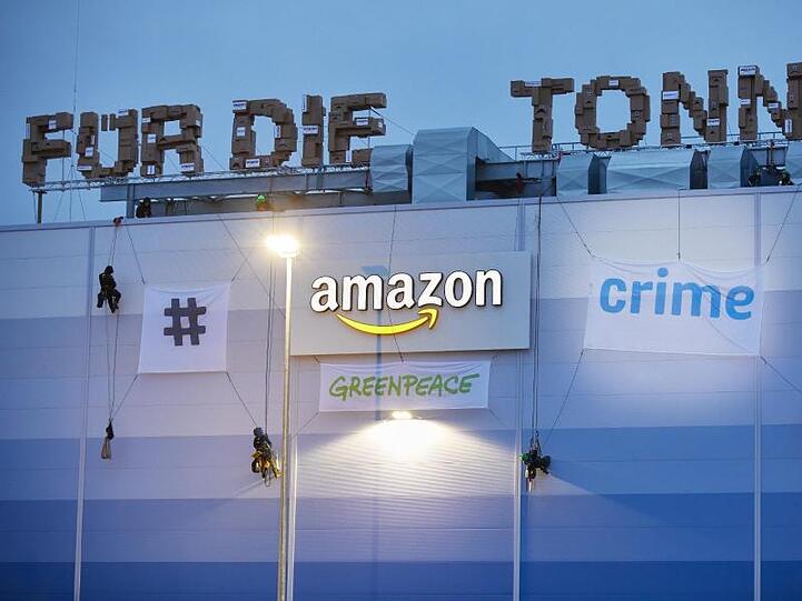 Greenpeace-Aktivisten hängen am Gebäude der Amazon-Logistik Winsen Transparente auf.
