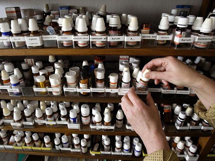 Blick in einen Schrank auf Fläschchen mit homöopathischen Präparaten. Foto: Frank Rumpenhorst/dpa/Archivbild