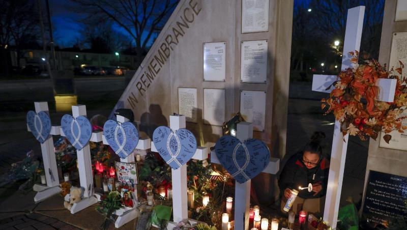 Eine Frau zündet Kerzen an einer Gedenkstätte im Veteran's Park für die Opfer an, nachdem ein Geländewagen am Sonntag in eine Weihnachtsparade gerast war, bei der mehrere Menschen getötet und Dutzende verletzt wurden.
