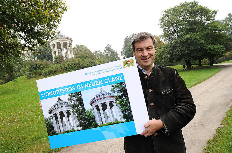 Monopteros-Restaurierung: Markus Söder präsentiert das Vorher-Nachher-Plakat.