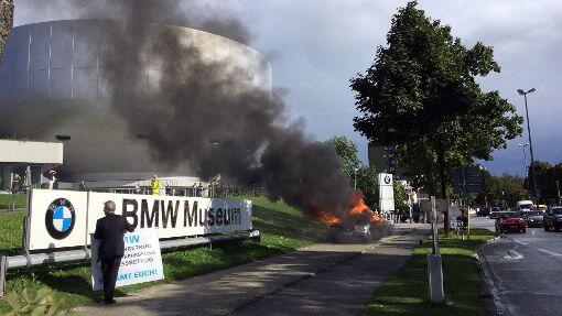 Protest bei BMW: Mit Plakat und brennendem Auto will Pourmohseni sich Gehör verschaffen. Foto: Regine Kruzinna