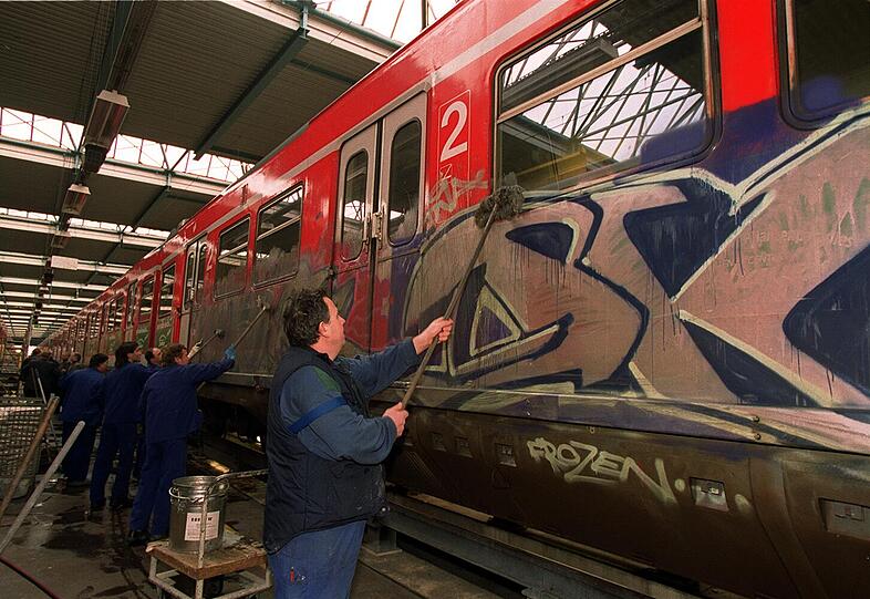 Arbeiter entfernen Graffiti an einer S-Bahn.