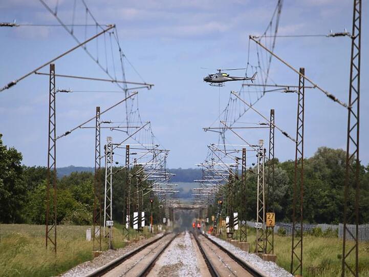 Ein Hubschrauber transportiert über der am Pfingstwochenende 2019 gesperrten Bahnstrecke Augsburg-Donauwörth einen Signalmasten der Bahn.