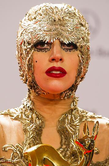 ...erschien sie wie zumeist in einer - nicht im klassischen Sinne schönen, dafür umso auffälligeren - Kreation, die Assoziationen an eine Ferrero-Rocher-Praline in einem Stummfilm des frühen 20. Jahrhunderts erweckte.