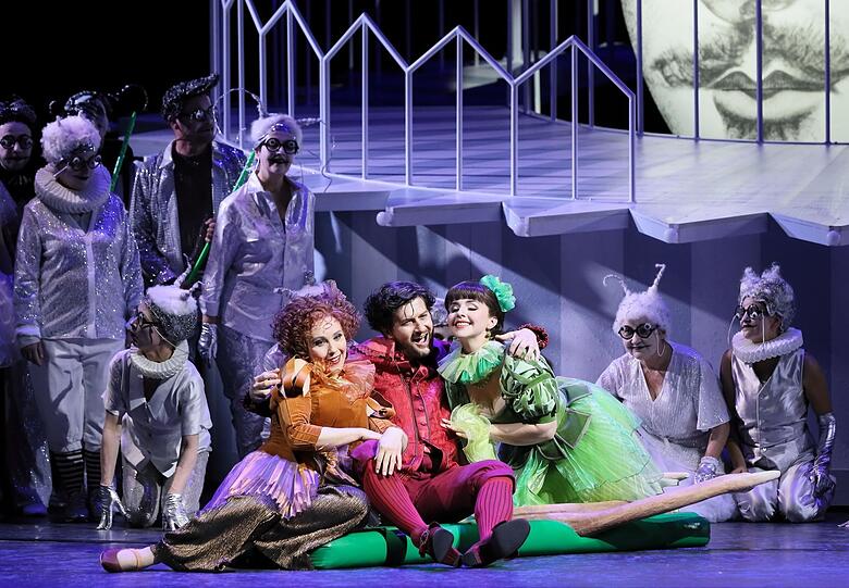 Jennifer O'Loughlin (Frau Fluth, links), Levente Páll (Sir John Falstaff) und Anna-Katharina Tonauer (Frau Reich) mit dem Chor des Staatstheaters.