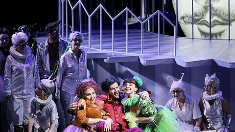 Jennifer O'Loughlin (Frau Fluth, links), Levente Páll (Sir John Falstaff) und Anna-Katharina Tonauer (Frau Reich) mit dem Chor des Staatstheaters.