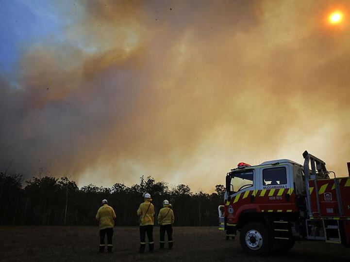 Feuerwehrleute beobachten im australischen Bundesstaat New South Wales die aus einem Waldgebiet aufsteigenden Rauchwolken.
