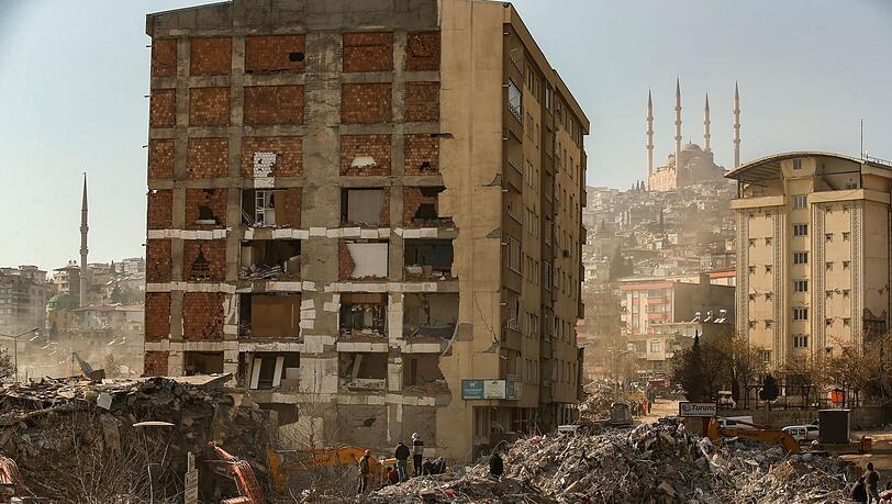 Menschen stehen im türkischen Kahramanmaras auf den Trümmern eines eingestürzten Gebäudes.
