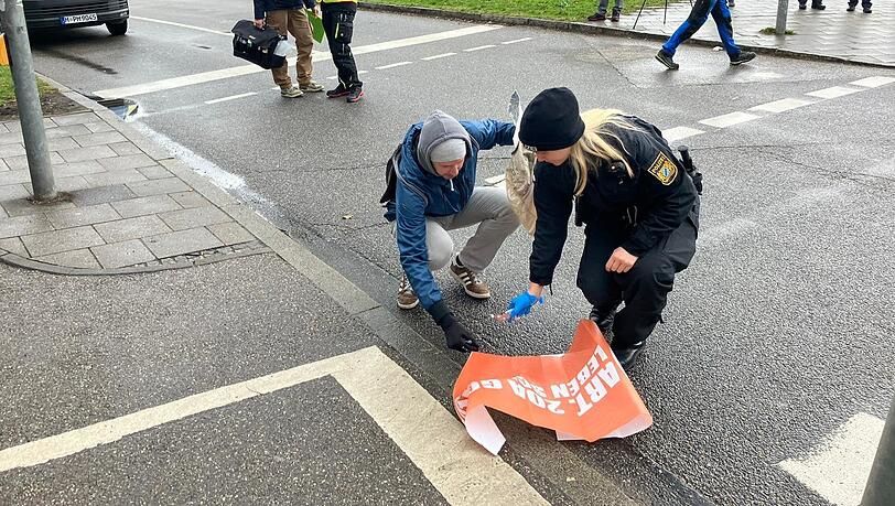 Eine Polizistin und ein Aktivist räumen zusammen.