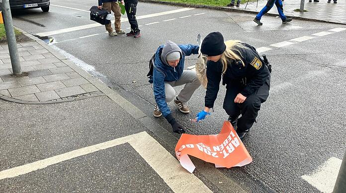 Eine Polizistin und ein Aktivist räumen zusammen.
