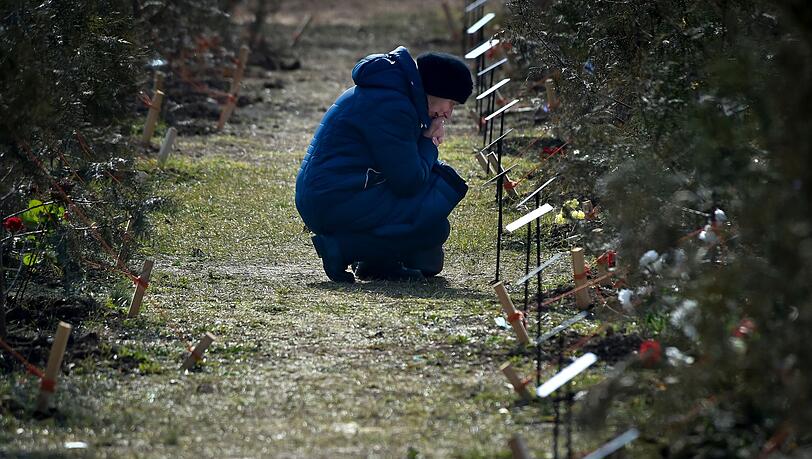 Die Mutter eines russischen Soldaten, der bei einer Militäraktion in der Ukraine getötet wurde, kniet neben einem Baum, der zum Gedenken an ihren Sohn in der Allee der Helden in Sewastopol auf der Krim gepflanzt wurde.