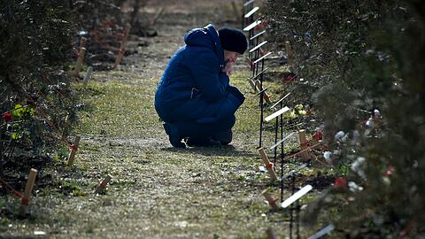 Die Mutter eines russischen Soldaten, der bei einer Militäraktion in der Ukraine getötet wurde, kniet neben einem Baum, der zum Gedenken an ihren Sohn in der Allee der Helden in Sewastopol auf der Krim gepflanzt wurde.