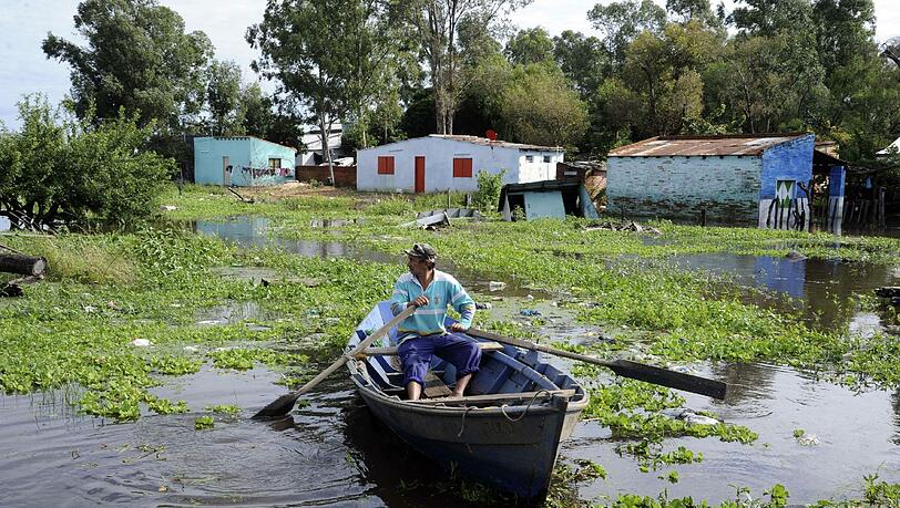 Ein Mann paddelt mit einem Boot über eine überflutete Straße in Asuncion (Paraguay). Von der Flut in dem südamerikanischen Land sind 17.000 Menschen betroffen. Ein Mann paddelt mit einem Boot über eine überflutete Straße in Asuncion (Paraguay). Von der Flut in dem südamerikanischen Land sind 17.000 Menschen betroffen.