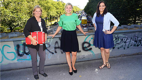 Auf der Fußgängerbrücke über der Landshuter Allee (v.l.): Ruth Waldmann (SPD) mit ihrem roten Bürgerkoffer, Katharina Schulze (Grüne) und Tina Pickert (CSU).