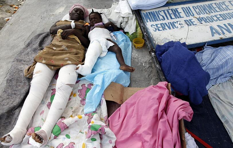 Eine verletzte Frau und ein verletztes Mädchen liegen nach dem Erdbeben am 12. Januar 2010 in einem improvisierten Krankenhaus in Port au Prince, Haiti.