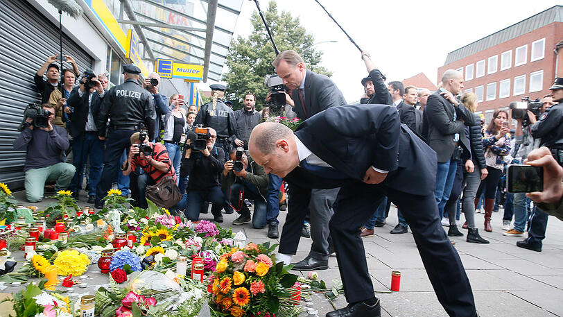 Blumen legt Hamburgs Erster Bürgermeister Olaf Scholz vor dem Tatort des Messerangriffs in Hamburg-Barmbek ab.