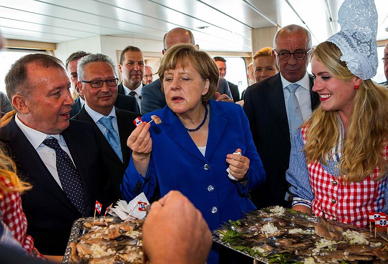 Dann gibt's endlich Fisch! Merkel wagt sich zunächst an ein kleines Stückchen Hering.