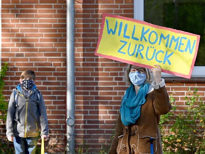 Eine Lehrerin in Schleswig-Holstein begrüßt ihre Schüler mit einem "Willkommen zurück"-Schild.
