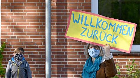 Eine Lehrerin in Schleswig-Holstein begrüßt ihre Schüler mit einem "Willkommen zurück"-Schild.