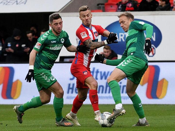 Heidenheims Niklas Dorsch (M) kämpft gegen Fürths Maximilian Wittek (l) und Havard Nielsen um den Ball.