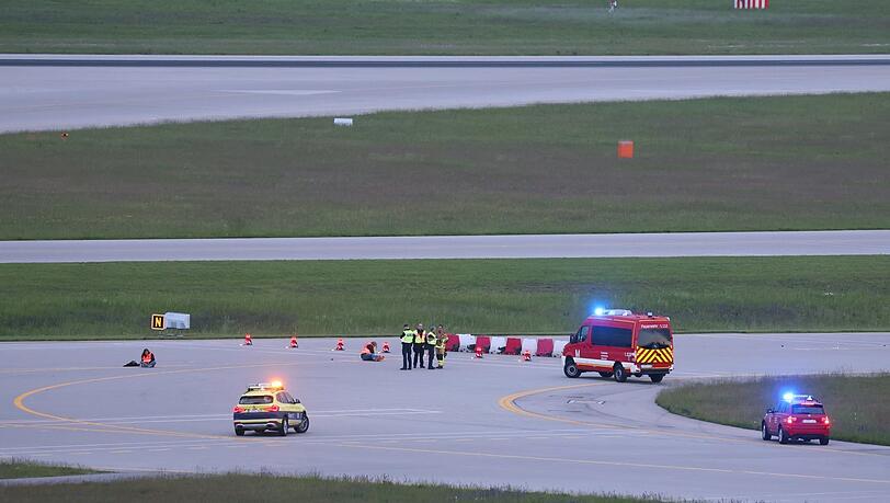 Einsatzkräfte von Polizei und Feuerwehr stehen am Samstag auf einer Startbahn des Flughafens.