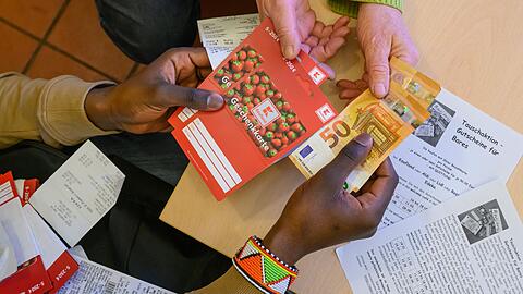 Ein junger Mann tauscht Super-Gutscheine gegen Bargeld. Wegen der Bezahlkarte ist das der einzige Weg für Geflüchtete, um an mehr als 50 Euro Bargeld zu kommen.