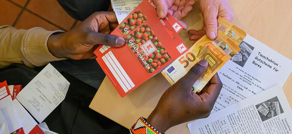 Ein junger Mann tauscht Super-Gutscheine gegen Bargeld. Wegen der Bezahlkarte ist das der einzige Weg für Geflüchtete, um an mehr als 50 Euro Bargeld zu kommen.
