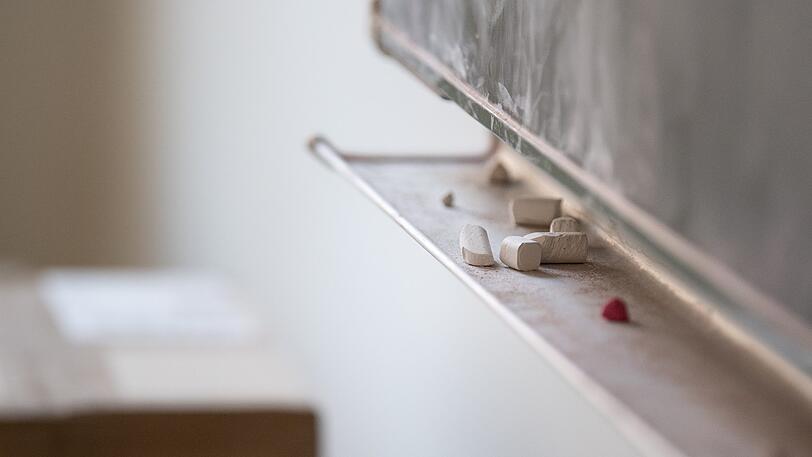 Kreide liegt unter einer Tafel in einem Klassenzimmer. (Symbolbild)