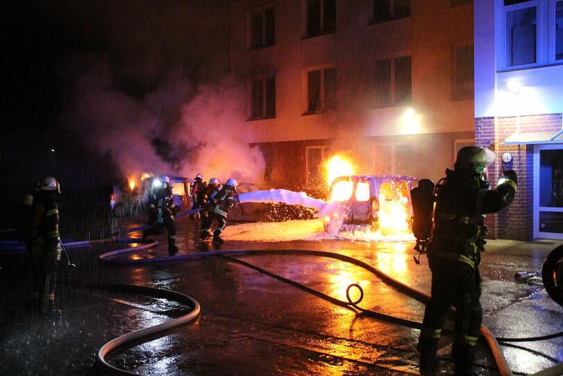 Feuerwehrleute löschen neben dem Rathaus in Barsinghausen (Niedersachsen) brennende Fahrzeuge. Zuvor hatten rund 1500 Menschen am Mittwoch nach dem Brandanschlag auf ein geplantes Flüchtlingsheim in Barsinghausen gegen Fremdenhass demonstriert.