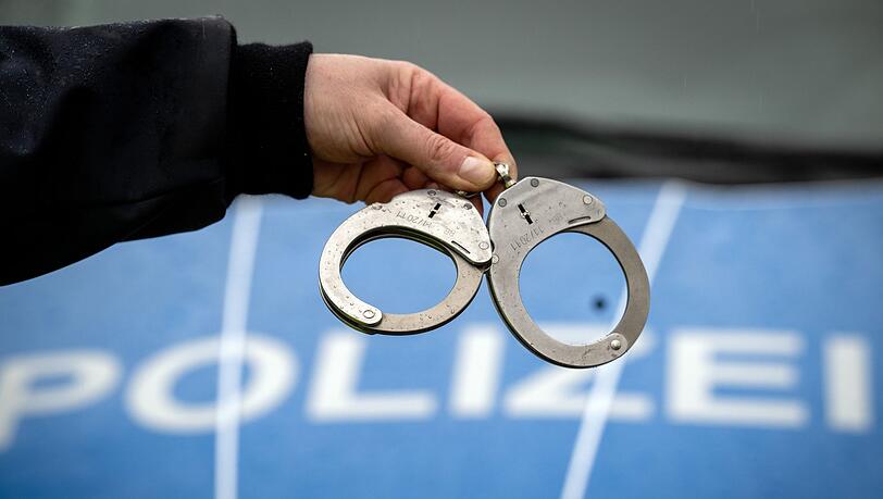 Ein Polizist hält ein Paar Handschellen.