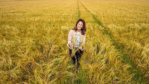 Michaela Kaniber (CSU) steht in einem Feld mit Wintergerste. Foto: Peter Kneffel/dpa