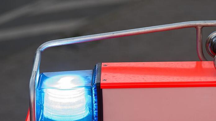 Ein Fahrzeug der Feuerwehr fährt mit Blaulicht über eine Straße.