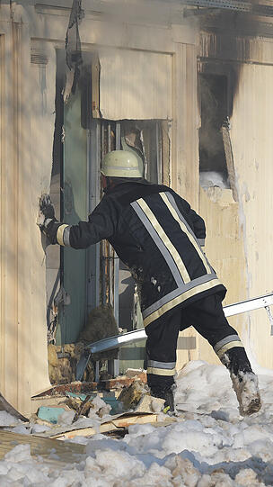Feuerwehrleute stehen vor ausgebrannten Wohncontainern. Nachts kam es in dieser Asylunterkunft aus unbekannter Ursache zu einem Brand, bei dem drei Bewohner verletzt wurden.