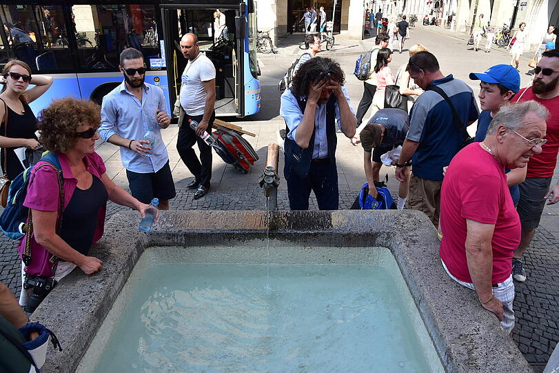 Kreislauf! Touristen haben den Trinkwasserbrunnen am Alten Rathaus entdeckt &ndash; und kühlen ihr Gesicht.