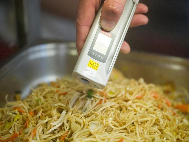 Ein Lebensmittelkontrolleur überprüft bei einer Betriebskontrolle die Temperatur von chinesischen Nudeln.