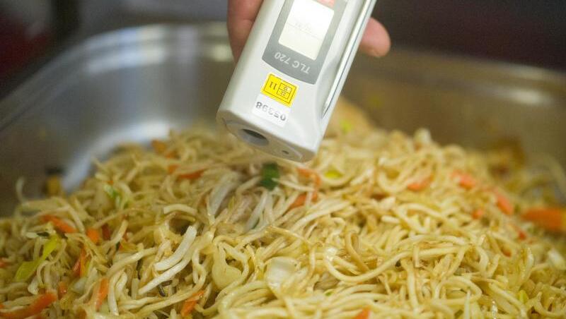 Ein Lebensmittelkontrolleur überprüft bei einer Betriebskontrolle die Temperatur von chinesischen Nudeln. Ein Lebensmittelkontrolleur überprüft bei einer Betriebskontrolle die Temperatur von chinesischen Nudeln.